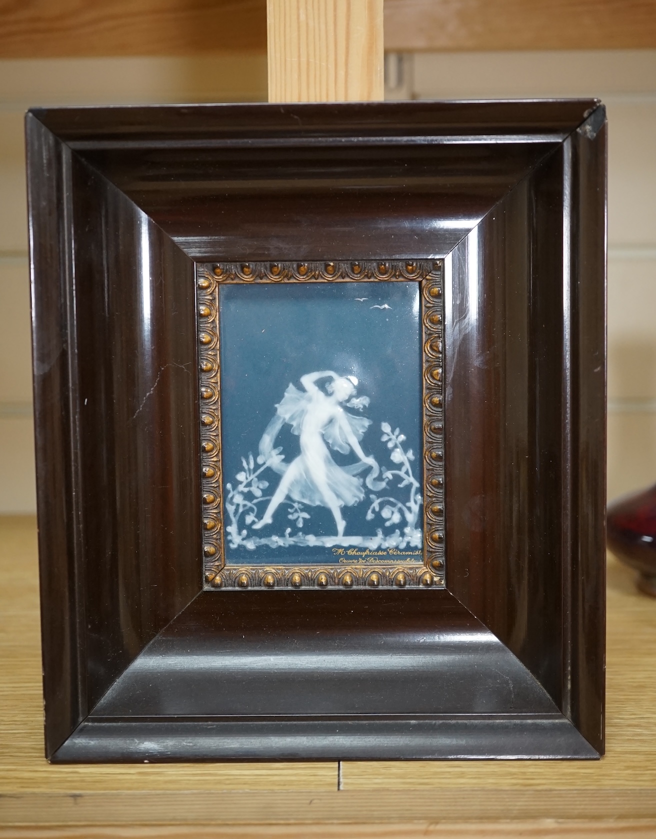 A framed Limoges blue and white pate-sur-pate plaque of a dancing fairy, signed Descomps, plaque 7cm x 10cm. Condition - good